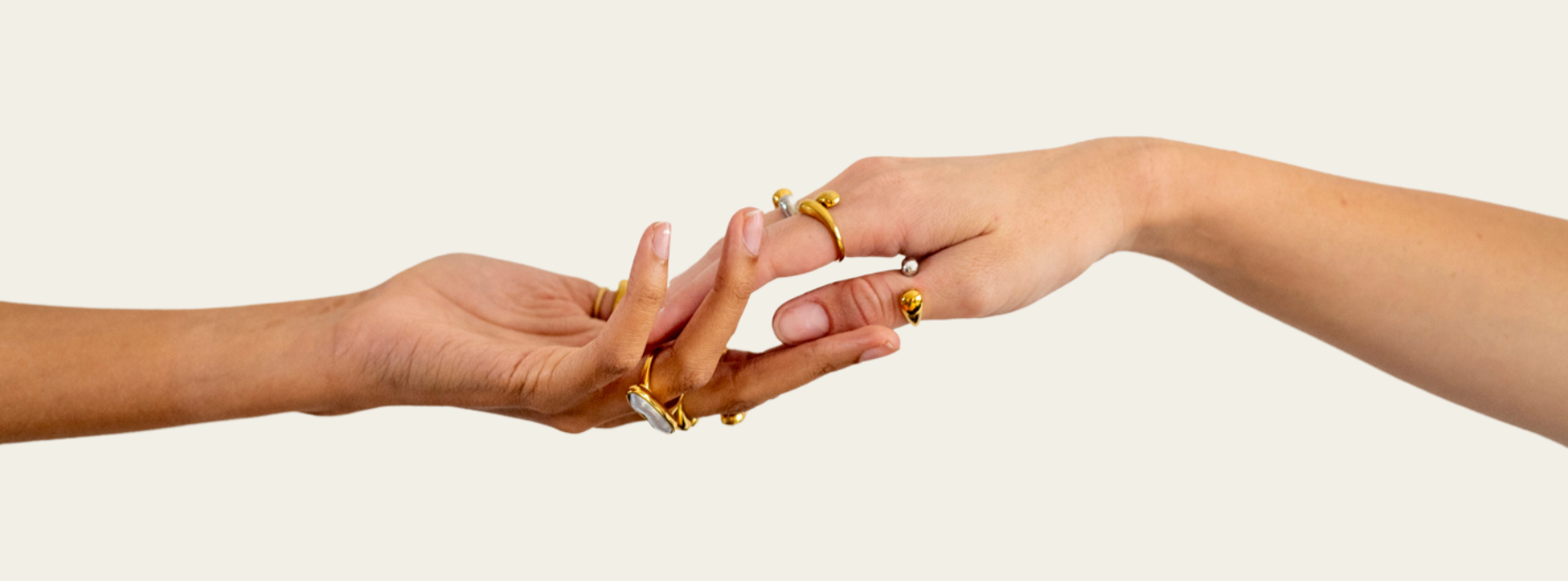 Two hands reaching towards each other with gold rings on a light background
